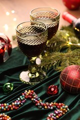 Glasses with red wine and beautiful Christmas decor on table, closeup
