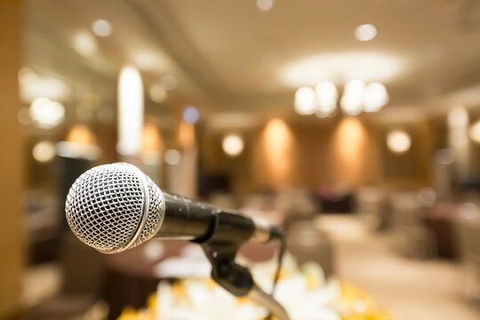 close-up of a microphone on a stage, essence of a dynamic conference or seminar, audience in the background, emphasizing interaction and speech microphone symbolizing audio excellence, leadership.