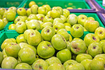 ripe sweet sour green apples in a container in a supermarket