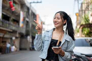 A female tourist standing by the street and pointing her finger upward as she recommends something.