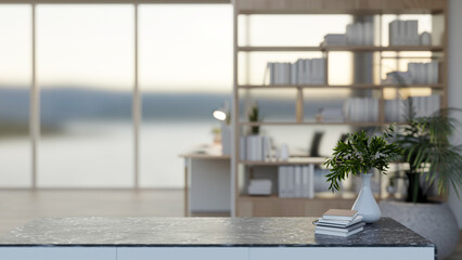 A close-up of a black marble desk in a modern room features a large bookshelf and window. © bongkarn