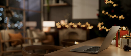 A close-up of a laptop and gift boxes on a table in a cozy home on a Christmas night.