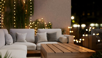 A cozy, beautiful apartment balcony at night, featuring a comfortable couch and glowing lights.