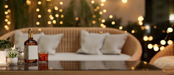 A whisky bottle and a glass on a coffee table in a beautiful living room or restaurant at night.