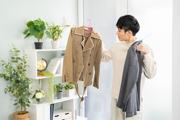 服を選ぶアジア人男性-白ベースのシンプルな部屋背景