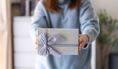 Woman holding a gift box with a ribbon for special occasions surprise birthday, christmas, new year, celebrations holidays present giving happiness festive event, elegant packaging thoughtful gesture