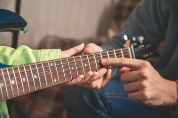 Playing a musical instrument. Father teaching daughter to play electric guitar. Close up