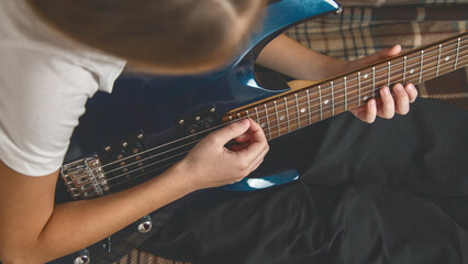 Fototapeta premium Girl playing electric guitar and practicing at home