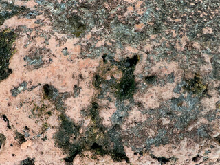 Close up of decaying and rustic stone texture. Brown pink stone oxidized and corroded with black molds and weathered pores, weathering mineral process. Seamless background texture.