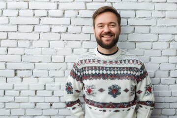 Obraz premium Happy man in Christmas sweater near white brick wall portrait.