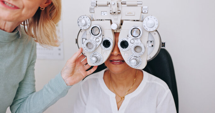 Doctor, optometry and woman on phoropter for eye care, consultation and hands in clinic for health exam. Ophthalmologist, test and patient on machine for vision check, wellness or eyesight correction