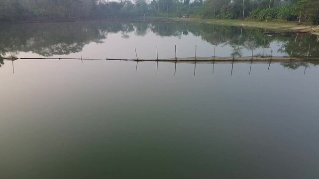 4k footage of a lake with calm water in the morning, covered in a thin mist