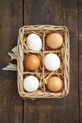 Rustic basket with white and brown eggs on a wooden table