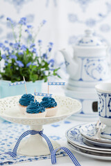 Elegant tea setup with blue cupcakes and floral decorations