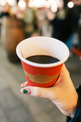 Woman hand holding glasses mugs with Germany red mulled wine on Christmas Market. The winter drink Traditional alcoholic drinks on German xmas funfair. Merry Christmas and happy New Year concept