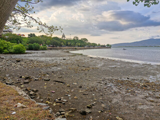 view of receding beach with cloudy sky and mountains in the background