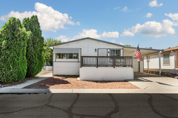 Bright and welcoming mobile home with porch and American flag in a peaceful community setting