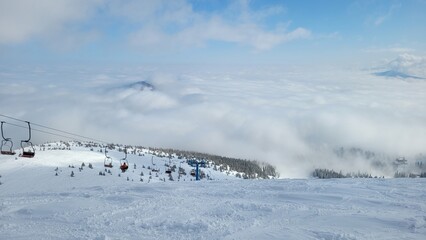 beautiful view from the top of the mountain, on the ski lift, and mountains in the clouds. Mountains covered with snow, winter