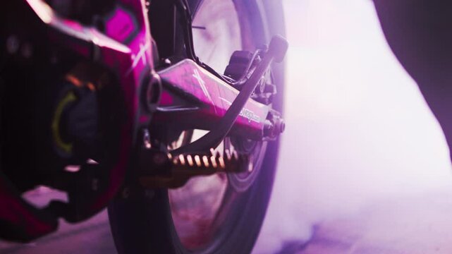 Close-up shot of the wheel on a dirt bike burning out in the middle of a large party with people around.