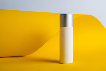 Plastic white tube for cream or lotion. Skin care or sunscreen cosmetic on yellow background.