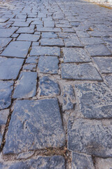 Close-up view of a cobblestone street, showcasing the intricate pattern created by the irregular shapes and sizes of the stones, rustic charm of the scene.