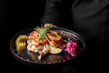 A gourmet dish featuring succulent chicken slices garnished with fresh rosemary, served alongside pickles and vibrant pink cabbage on a sleek black plate, perfect for food lovers.
