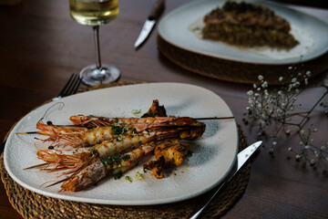tasty grilled combo shrimps with garlic butter sauce served with mushrooms and white wine in rustic restaurant, real life dining concept