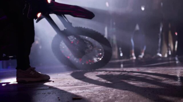 Shot of a dirt bike stuntman doing donuts with his bike in front of a crowd.