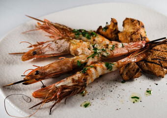 grilled shrimps with mushrooms and butter garlic saouce served on sticks topped by mediterranean herbs , white plate and background