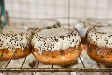 A rack of donuts with a plastic covering on them, Easter baking at the factory
