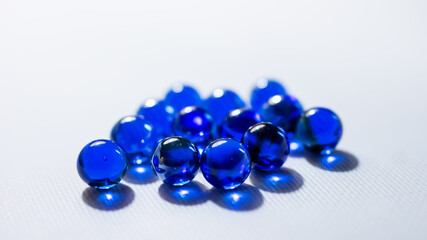 A large collection of vibrant blue marbles displayed on a white surface