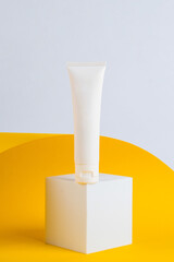 Cosmetic product in tube, bottle, lotion or serum on yellow background with stylish props. 