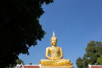 Fototapeta premium Beautiful big Golden Buddha statue under clear and sunny sky in Khueang Nai District, Ubon Ratchathani, Thailand
