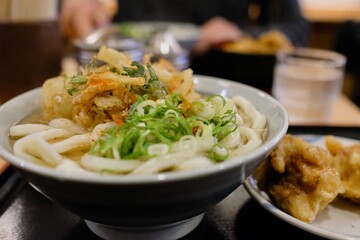 A bowl of vegetable tempura udon noodle soup and karaage chicken at a small shokudo (eatery) in Shinjuku - Tokyo, Japan