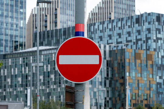A vibrant no entry road sign stands prominently in front of impressive contemporary buildings, emphasizing the intersection of urban regulations and modern architecture.