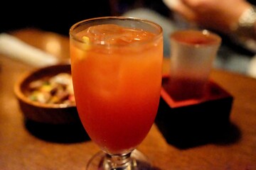 A tequila sunrise cocktail and glass of hot sake served with roasted nuts at Vagabond, a a jazz cafe and “drinking den” with live music in Shinjuku - Tokyo, Japan