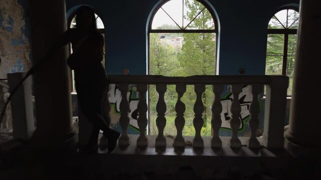 Aerial pulls back past woman in hallway of abandoned sanatorium Iveria