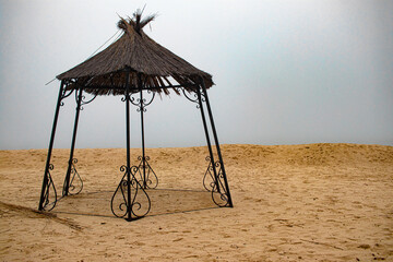 Mist. Beach. End of season. Empty gazebo.