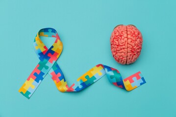 Fototapeta premium World Autism awareness and pride day. Anatomical model human brain with Puzzle pattern ribbon on blue background.