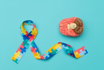 World Autism awareness and pride day. Anatomical model human brain with Puzzle pattern ribbon on blue background.