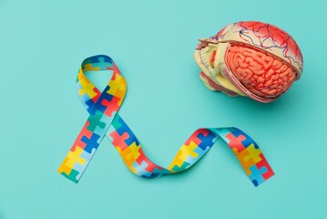 World Autism awareness and pride day. Anatomical model human head with Puzzle pattern ribbon on blue background.