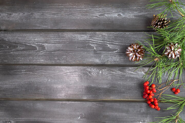 Fototapeta premium Wooden background with spruce branches, cones and rowan berries. Natural Christmas decor