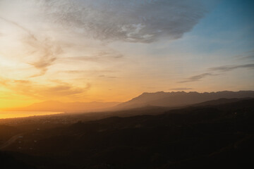  Softly lit hills and distant mountains under a golden sunset, creating a peaceful natural landscape