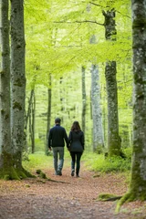 Couple walking away holding hands in beautiful green forest