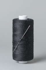 Black thread spool with needle close-up flat lay top view white background with copy space for text
