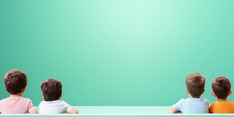 Four children sitting side by side on a green surface gaze intently in the same direction, embodying a sense of unity, curiosity, and the joy of childhood exploration.