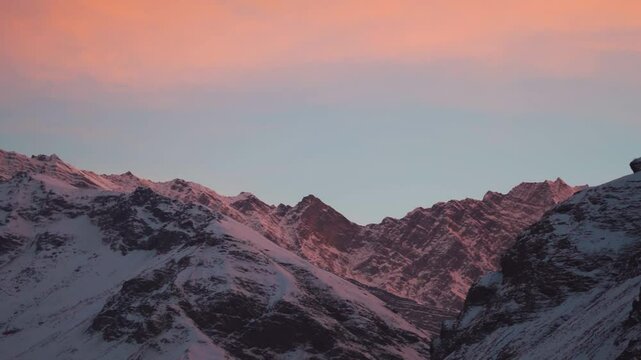 Orange clouds above the snowy Himalayan mountain peak during sunset in the winter season at Sissu village in Lahaul valley, Himachal Pradesh, India. Scenic view of Himalayas in winter season.