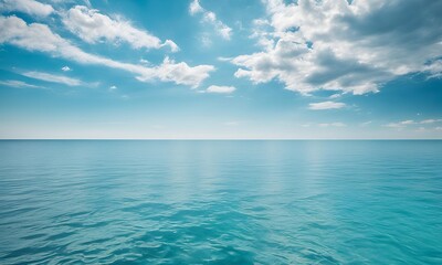 Calm blue ocean under a bright sky with fluffy clouds.