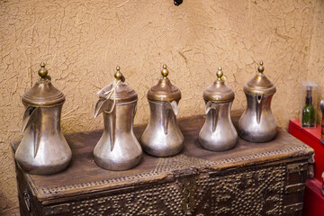 Five antique silver coffee pots displayed on a rustic wooden chest. A captivating image of cultural...