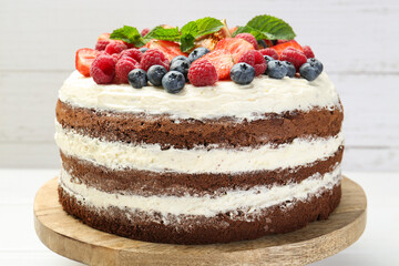 Delicious chocolate sponge cake with berries on light table, closeup